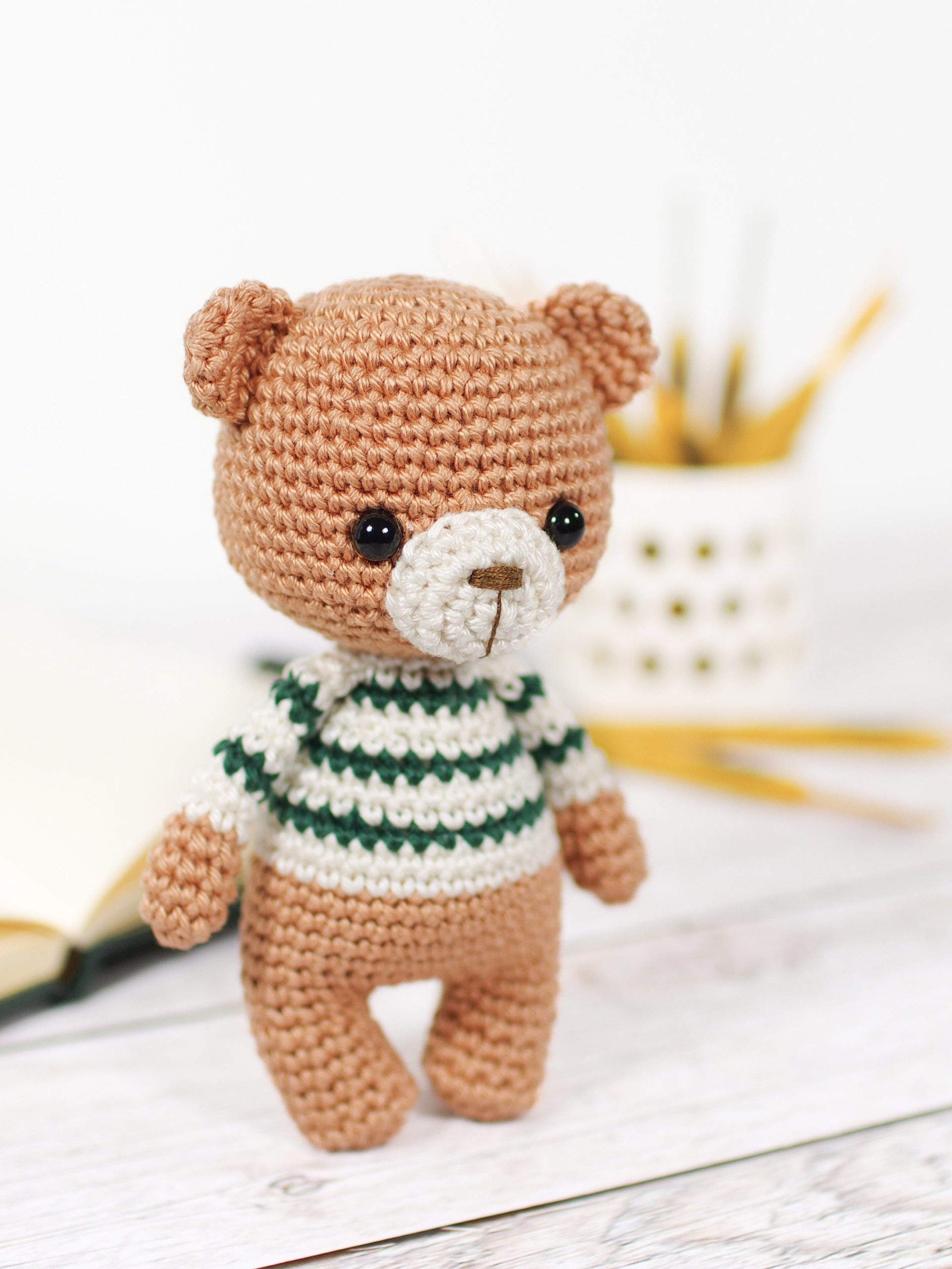 A cute crochet bear wearing a handmade striped sweater and a tiny bow tie