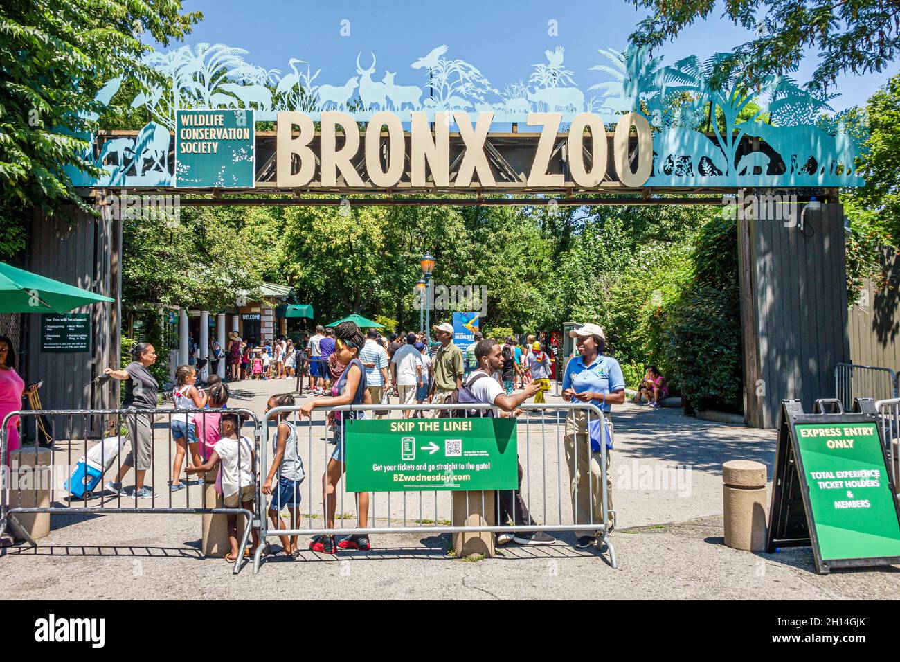 A bustling zoo entrance with visitors purchasing tickets