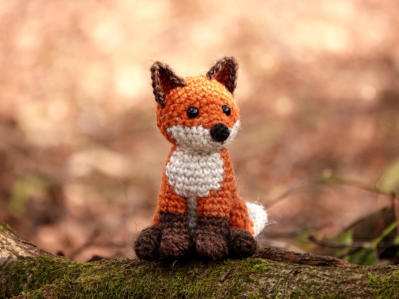 A detailed closeup of a crocheted fox face showcasing realistic embroidery and eye placement